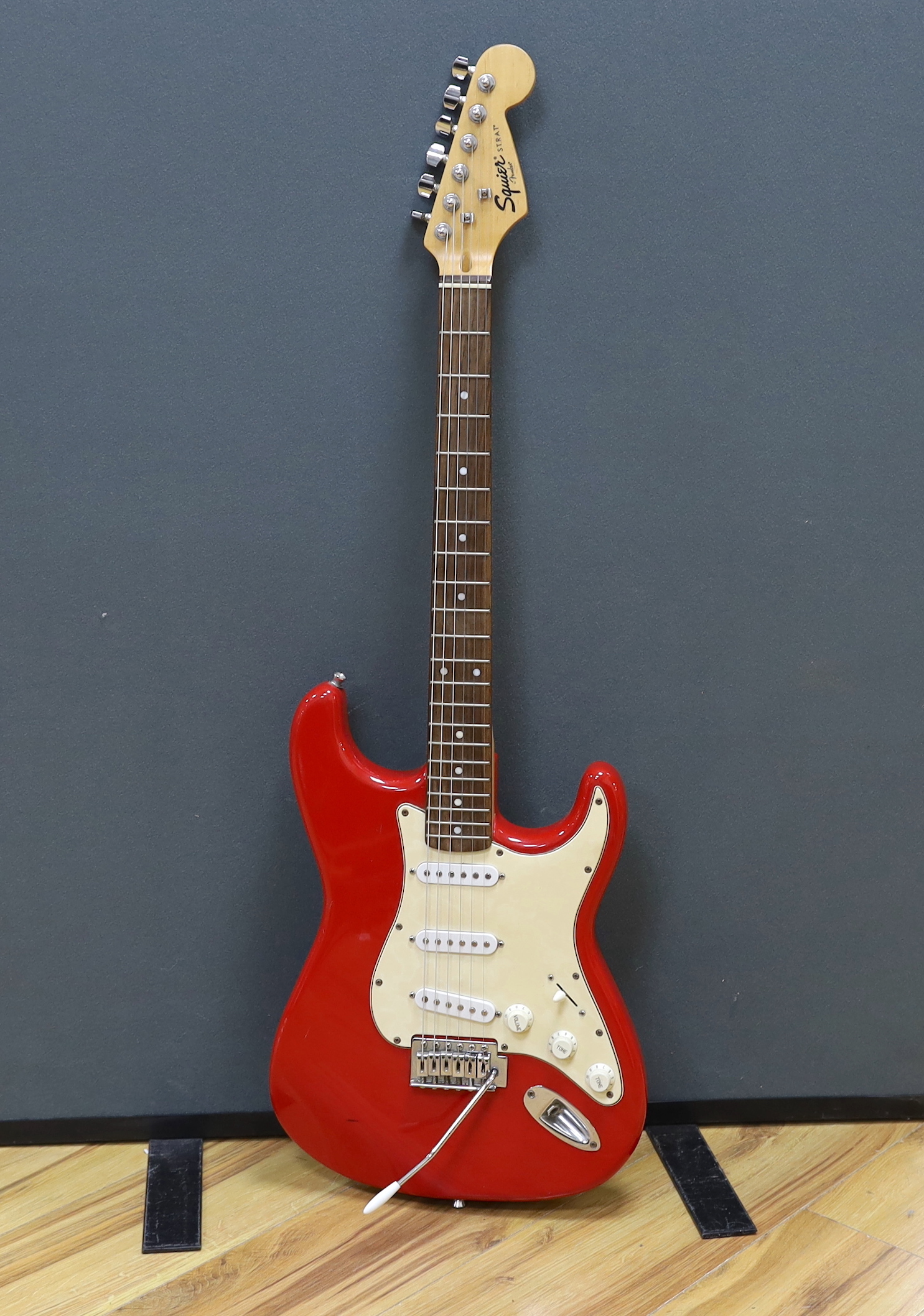 A Squier Strat by Fender electric guitar with rosewood neck and red lacquer body